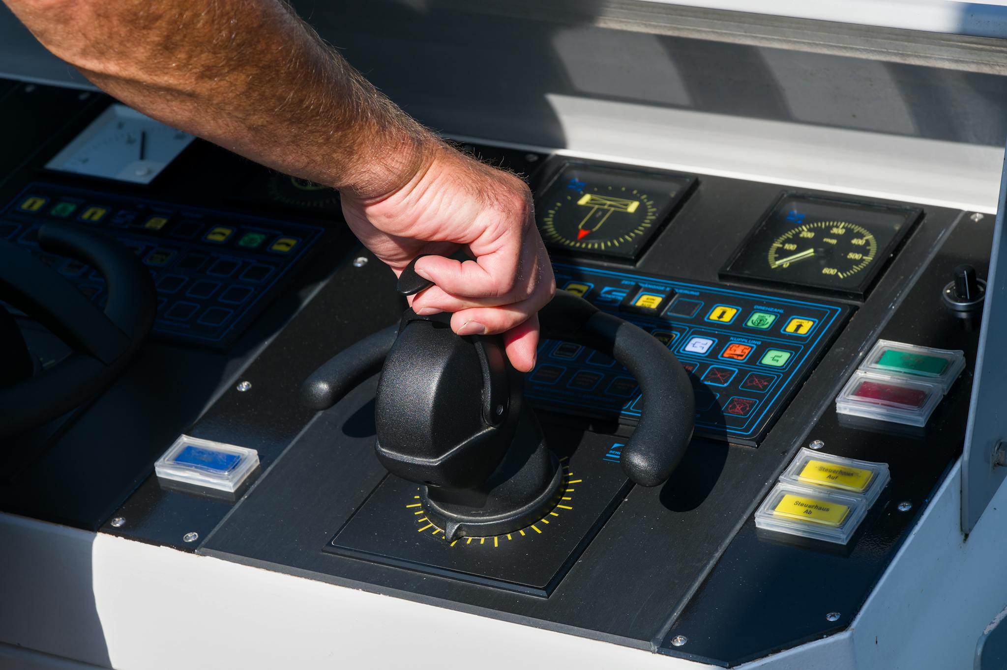 A close-up view of a hand managing a boat's control panel, emphasizing precision and control.